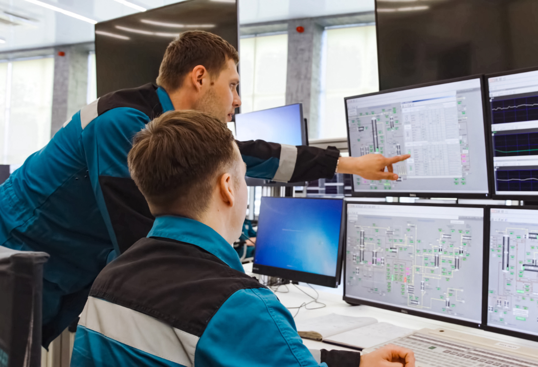 Two technicians use computers to monitor the performance of a locomotive in real time, showcasing the benefits of remote condition-based monitoring for locomotive haulage.